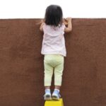 壁の向こうをのぞく子ども