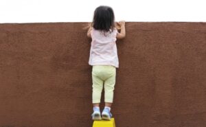 壁の向こうをのぞく子ども