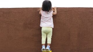 壁の向こうをのぞく子ども